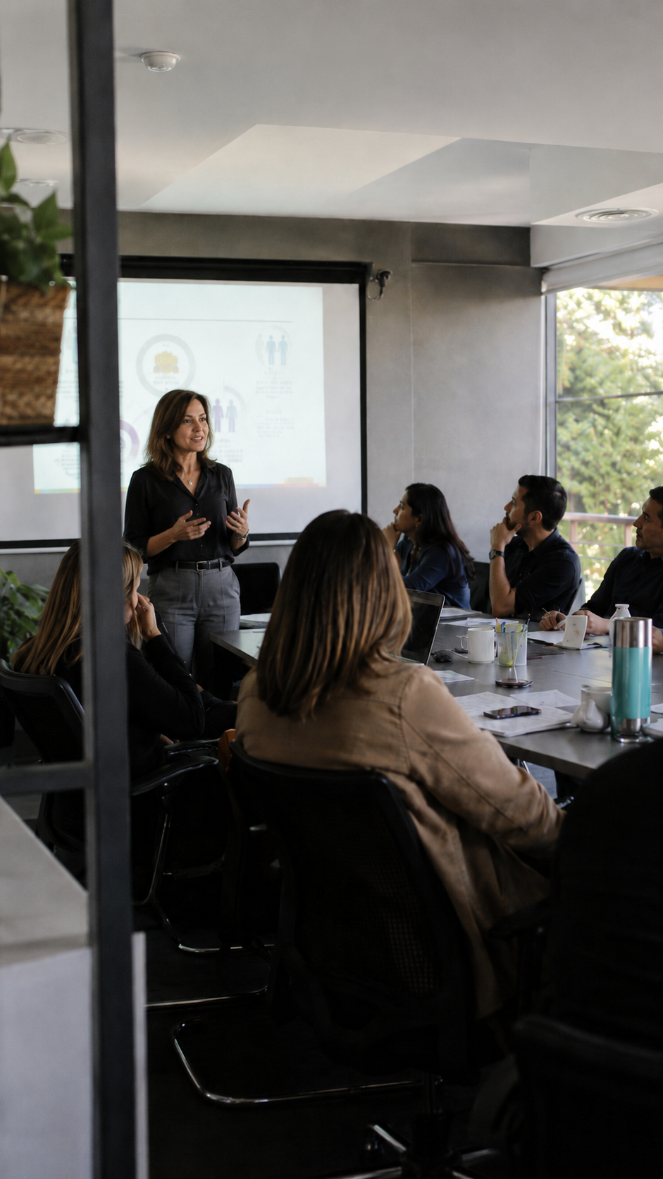 Facilitadora presentando ante un equipo reunido en una mesa de trabajo.